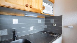 A kitchen with wooden cabinets, a black sink, a microwave, and a stove. - Asters 1208 Batiment B4 by Interhome (Les Menuires)