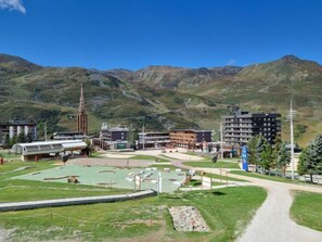 A mountainous area with a modern building complex, including a tall tower, and a sports field. - Asters 1208 Batiment B4 by Interhome (Les Menuires)