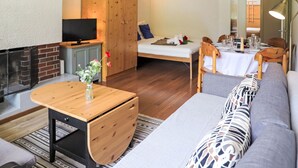 Una sala de estar acogedora con un sofá, una mesa de centro de madera, un televisor y una chimenea.