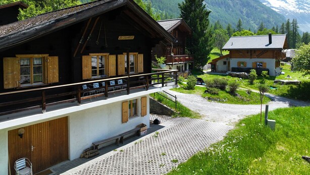 A chalet with a balcony overlooking a mountain path, wooden shutters, and a stone-paved entrance. - Coquelicot by Interhome (Zinal)