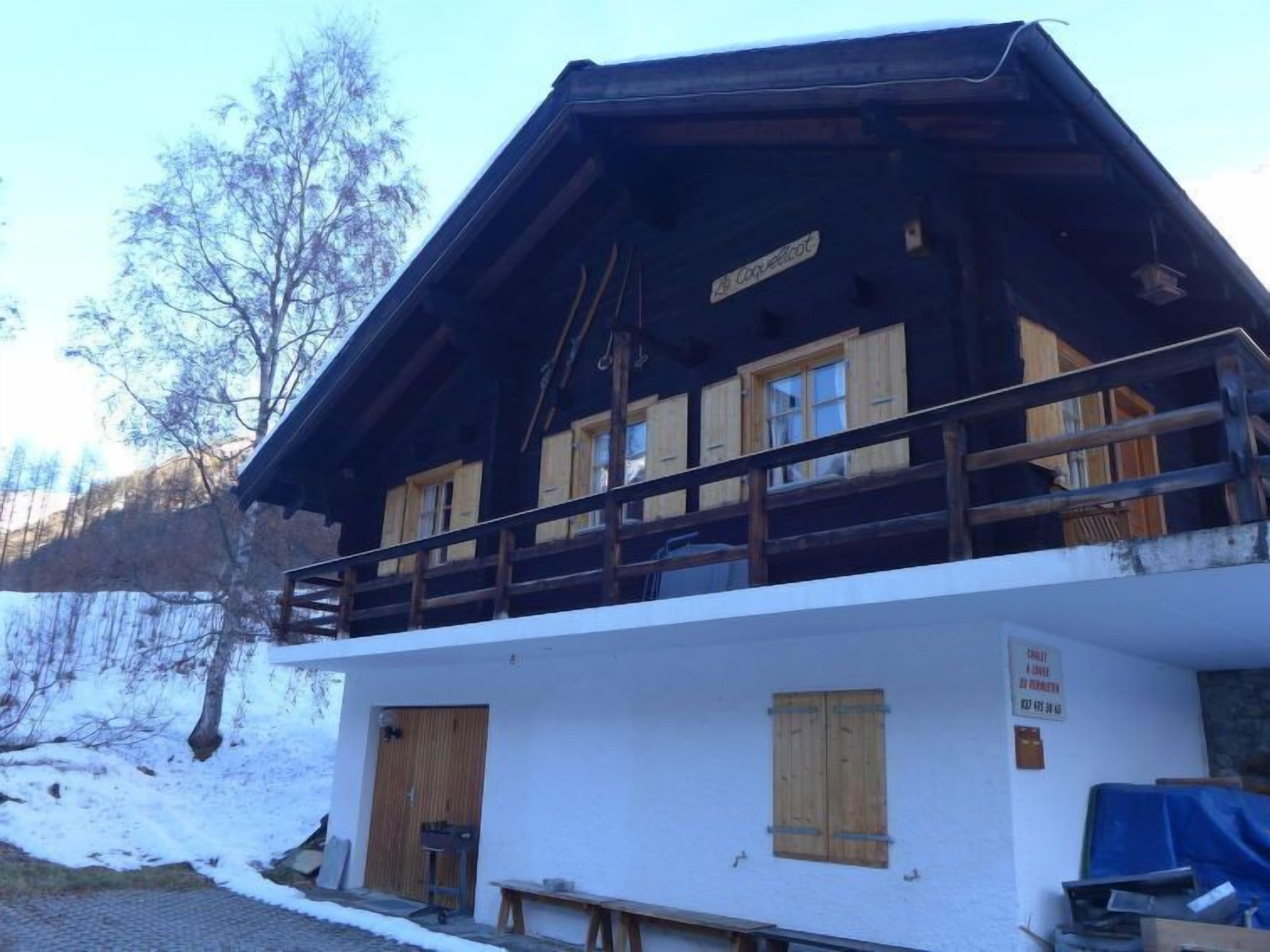 A chalet-style building with a wooden balcony, wooden shutters, and a sign indicating a restaurant.