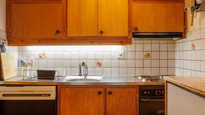 A kitchen with wooden cabinets, a dishwasher, and a stove. - Coquelicot by Interhome (Zinal)