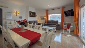 A dining area with a table set for four, a sofa, and a TV mounted on the wall. - Vacation home Sandra by Interhome (Albir)