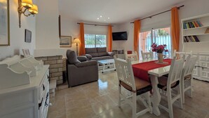 A spacious living area with a sofa, dining table, and chairs, a television, and a bookshelf. - Vacation home Sandra by Interhome (Albir)