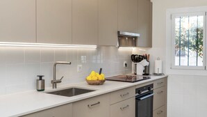 Eine moderne Küche mit Backofen, Spüle und Fenster mit Blick auf Grünfläche.
