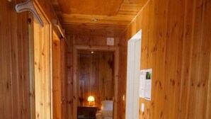 Un couloir en bois, avec un lit et une table de chevet en arrière-plan.