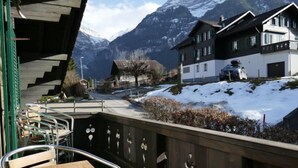 Une vue sur un paysage montagneux, avec des pentes enneigées et un bâtiment doté d’un balcon.