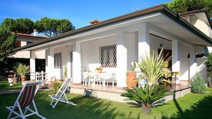 Una casa blanca con porche cubierto, mobiliario exterior y plantas en macetas.