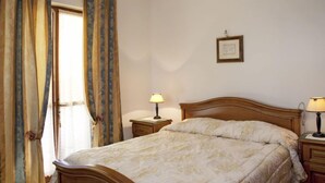 Un dormitorio con una cama de madera, dos mesitas de noche con lámparas, un candelabro y cortinas.
