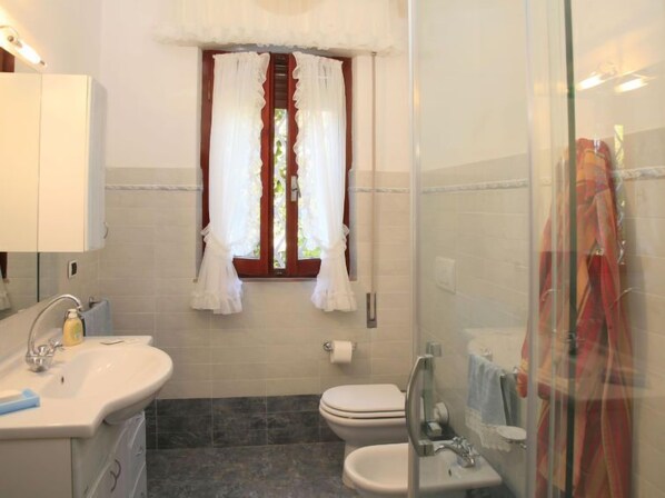 A bathroom with a sink, toilet, and shower area.