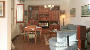 Una sala de estar acogedora con comedor, un sofá, un televisor y una estantería.