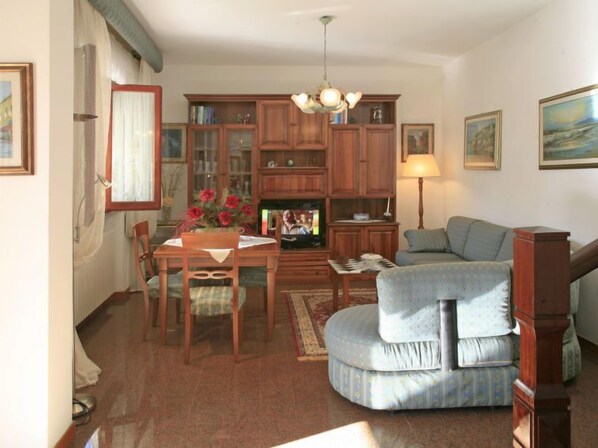 Una sala de estar acogedora con comedor, un sofá, un televisor y una estantería.