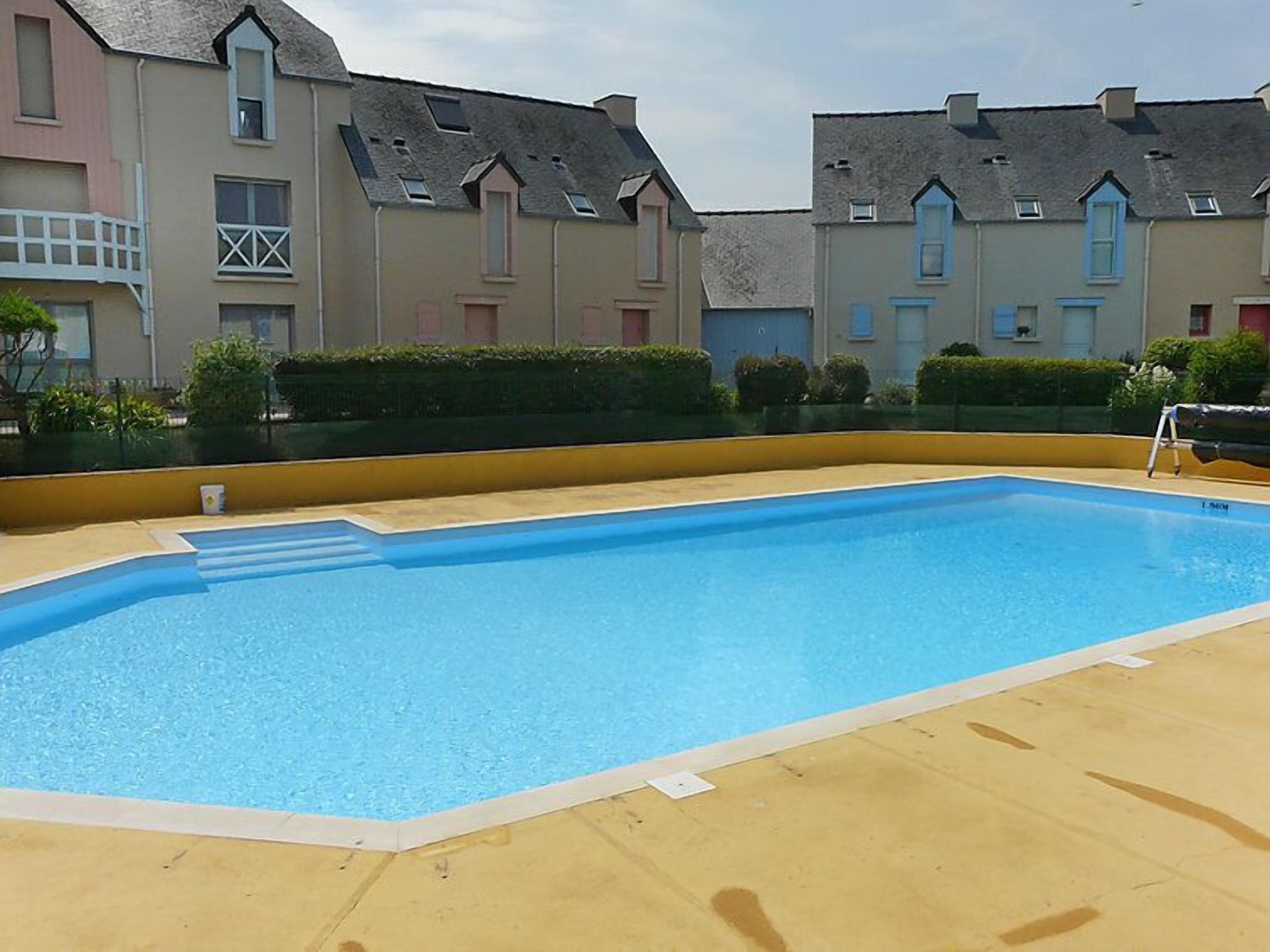 A rectangular swimming pool with a clear blue water surface, surrounded by a beige deck.