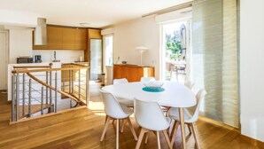 A modern kitchen with a dining area, wooden flooring, and a staircase leading to an upper level. - Cap Marine by Interhome (Cavalaire)