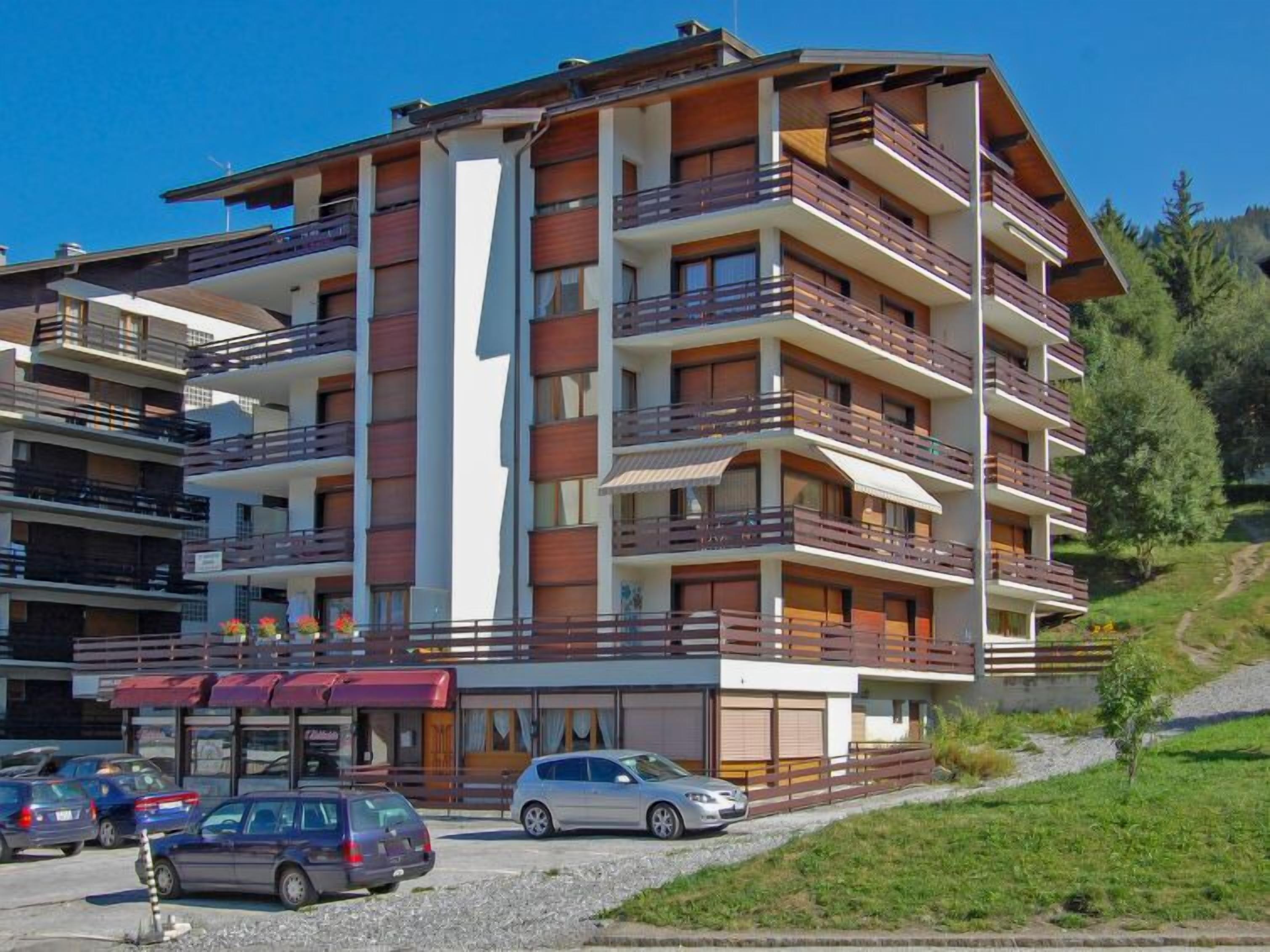 Ein mehrstöckiges Hotel mit Balkonen, einem überdachten Parkbereich und Blick auf die umliegende Landschaft.