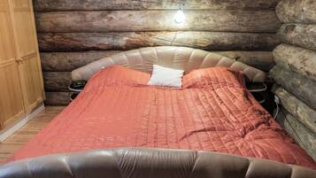 A log cabin room with a bed, a bedside table, and a clock.