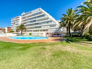 A modern hotel with a swimming pool, palm trees, and a bar.