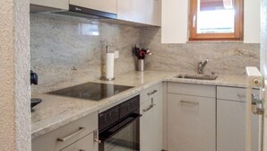 Una cocina con encimera de granito, electrodomésticos de acero inoxidable y armarios blancos.