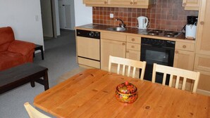 A compact kitchen with wooden cabinets, a tiled backsplash, a stove, and a dishwasher.