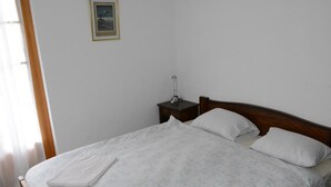 A neatly made bed with a wooden headboard, a bedside table with a lamp, and a framed picture on the wall.