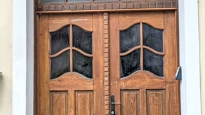 Une porte à deux battants en bois, dotée de panneaux de verre et d’une poignée en métal.