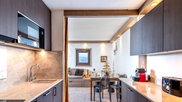 Une cuisine moderne avec des meubles de couleur bois foncé, un plan de travail en marbre et un four à micro-ondes encastré.