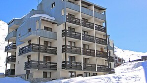 Un hôtel à plusieurs étages, doté de balcons, situé dans une région enneigée.