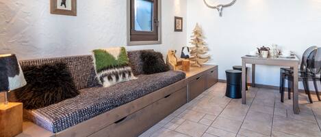 A cozy living area with a sofa, a small table with a coffee set, and a decorative tree.