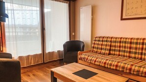 Ein gemütliches Wohnzimmer mit einem karierten Sofa, einem dunklen Sessel und einem Holztisch.