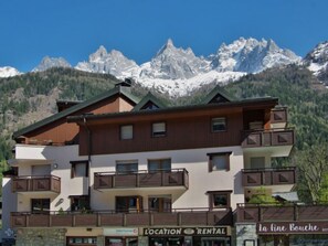 A multi-story building with balconies, a restaurant named "La Fine Bouche," and a sign for "Interhome" and "L'LOCATION RENTAL." - L'Espace Montagne by Interhome (Chamonix)