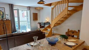 Ein Essbereich mit einem Holztisch, gedeckt für vier Personen, einer Holztreppe und Blick auf den Außenbalkon.