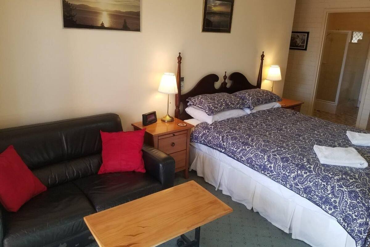 Une chambre d’hôtel avec un lit, un canapé, une table de chevet et une table.