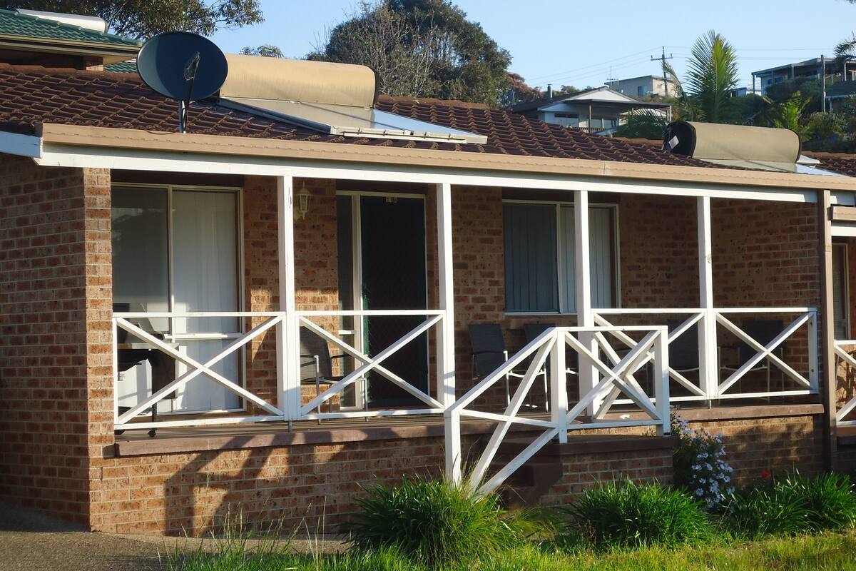 Une maison en briques avec un balcon, une antenne parabolique et un panneau solaire.
