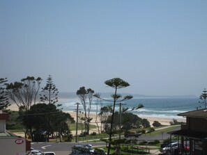 Une vue sur la côte, avec une plage, des arbres et une route menant à un bâtiment sur lequel on peut voir une enseigne.