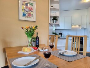 Une table à manger dressée avec des assiettes, des couverts, un verre de vin rouge, une bouteille de vin et un bouquet de tulipes.