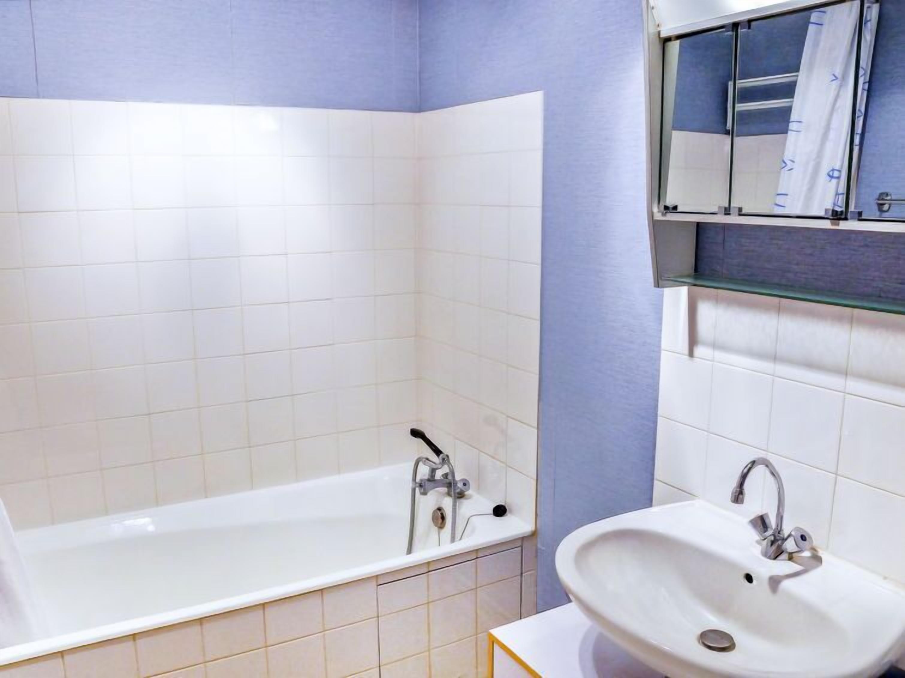 A modern bathroom with a bathtub, a sink, and a mirror.