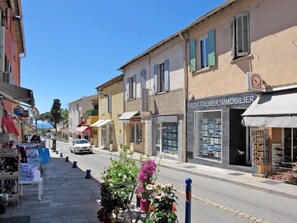 Une rue bordée d’immeubles, dont une agence immobilière et un magasin vendant des articles pour les activités de plein air.
