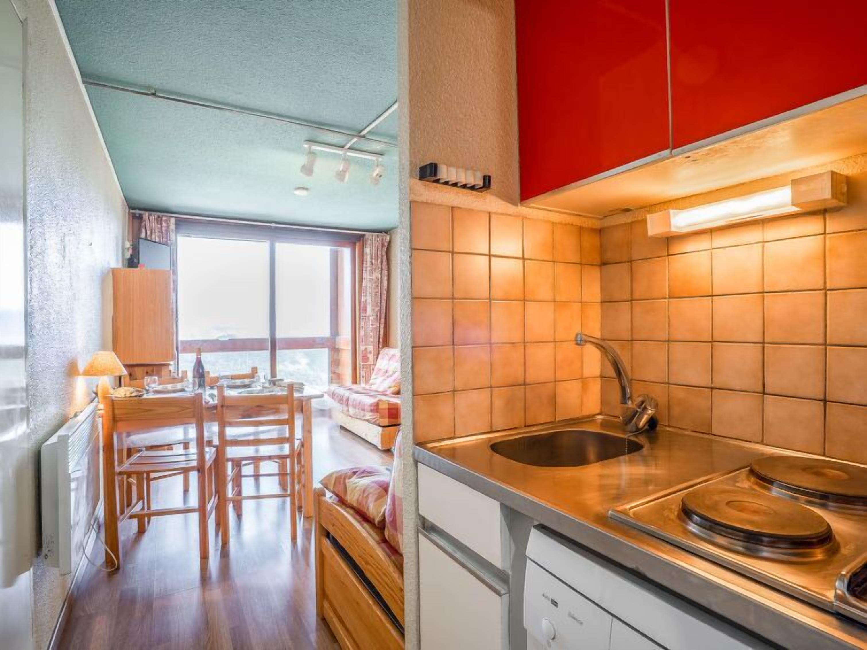 A compact kitchen with a sink, stove, and wooden dining area.