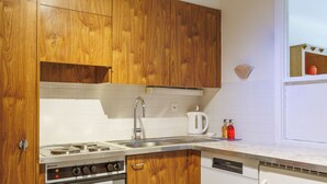 A compact kitchen with wooden cabinets, a gas stove, a dishwasher, and a kettle. - Rossignol C4 by Interhome (Nendaz)
