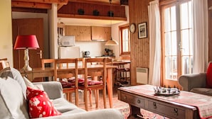 A cozy living room with a sofa, a coffee table, and a dining area with wooden furniture.