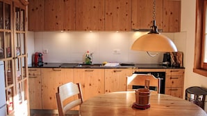 A kitchen with wooden cabinets, a round dining table, and a hanging light fixture.