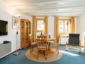 Ein Essbereich mit rundem Tisch, Stühlen, einem Schrank und einem Fernseher.