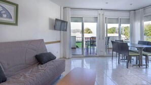 Een moderne woonkamer met een bank, een televisie en een balkon met een eethoek.