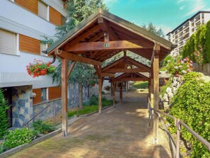 Un espacio al aire libre techado con estructura de madera, paredes de piedra y plantas en macetas.