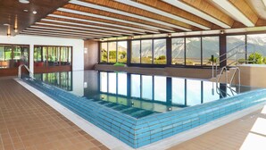 Piscina interior con vistas despejadas a montañas a través de grandes ventanales.