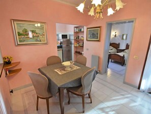 A dining area with a table and chairs, a kitchen in the background, and a bedroom visible through an open door. - Apartment Valier by Interhome (Venice)