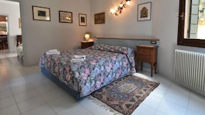 A bedroom with a large bed, a bedside table, a nightstand, a radiator, and framed pictures on the wall. - Apartment Valier by Interhome (Venice)