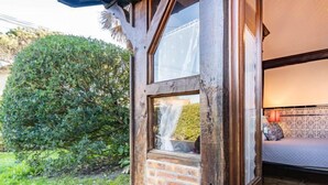 Ein Zimmer mit einem großen Fenster, einer Ziegelwand und Blick auf einen Garten.