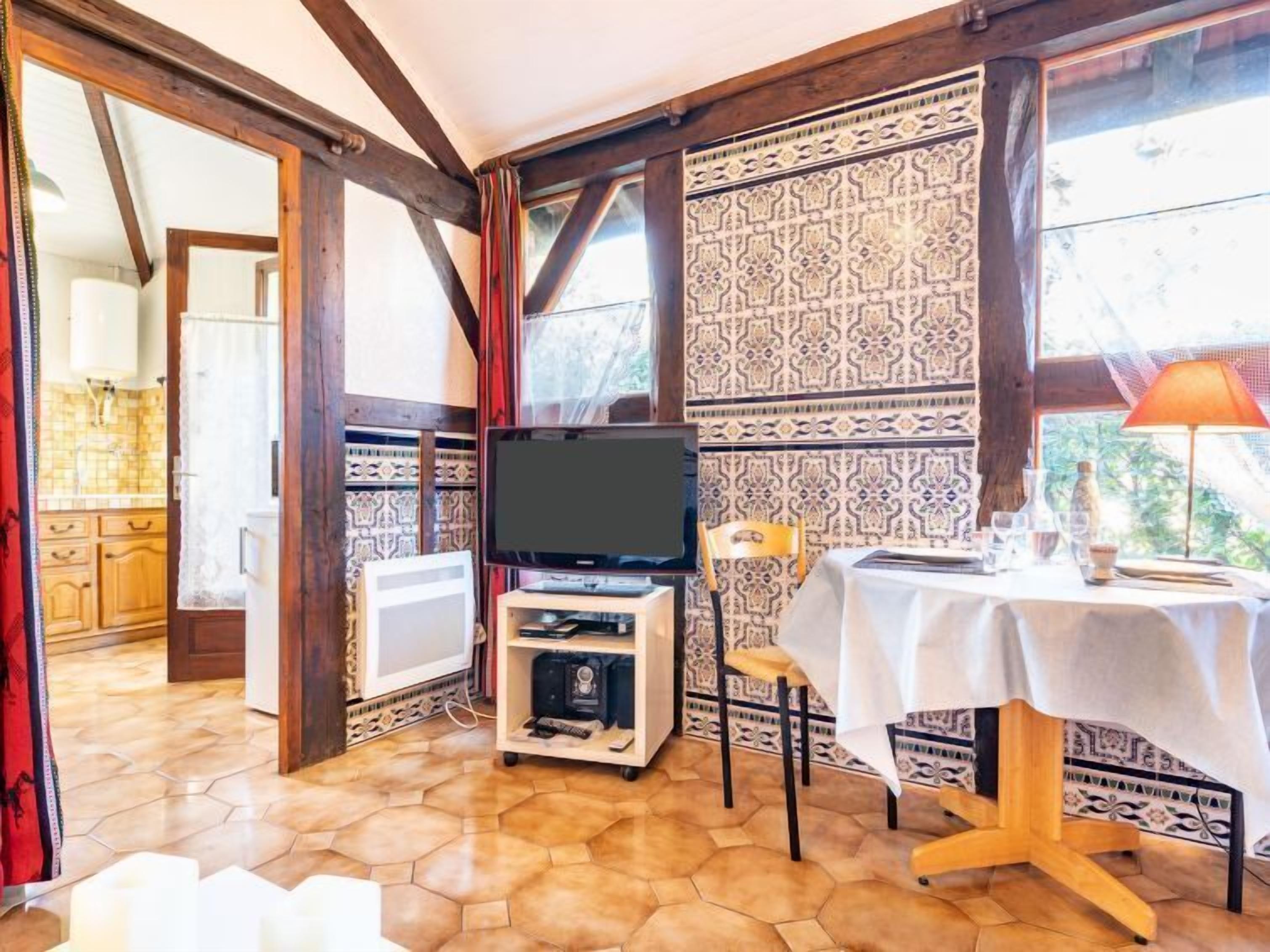Een knus ogende kamer met een televisie, een tafel met tafelkleed en behang met patroon.