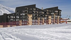 Un edificio de varios pisos con balcones, probablemente un hotel o conjunto de apartamentos, en un paisaje nevado.